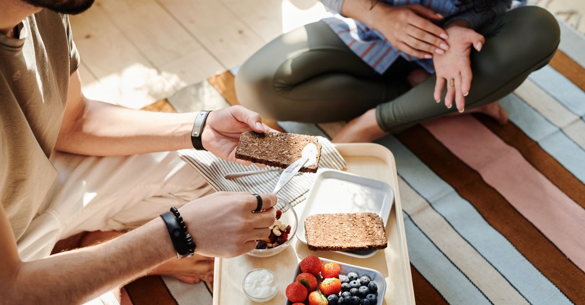 High angle view of a couple having a healthy breakfast with bread and fruits indoors.